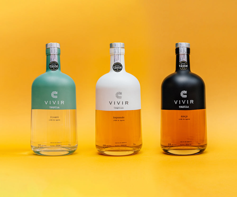 Three bottles of VIVIR Tequila are positioned in a row amongst a vibrant yellow background.