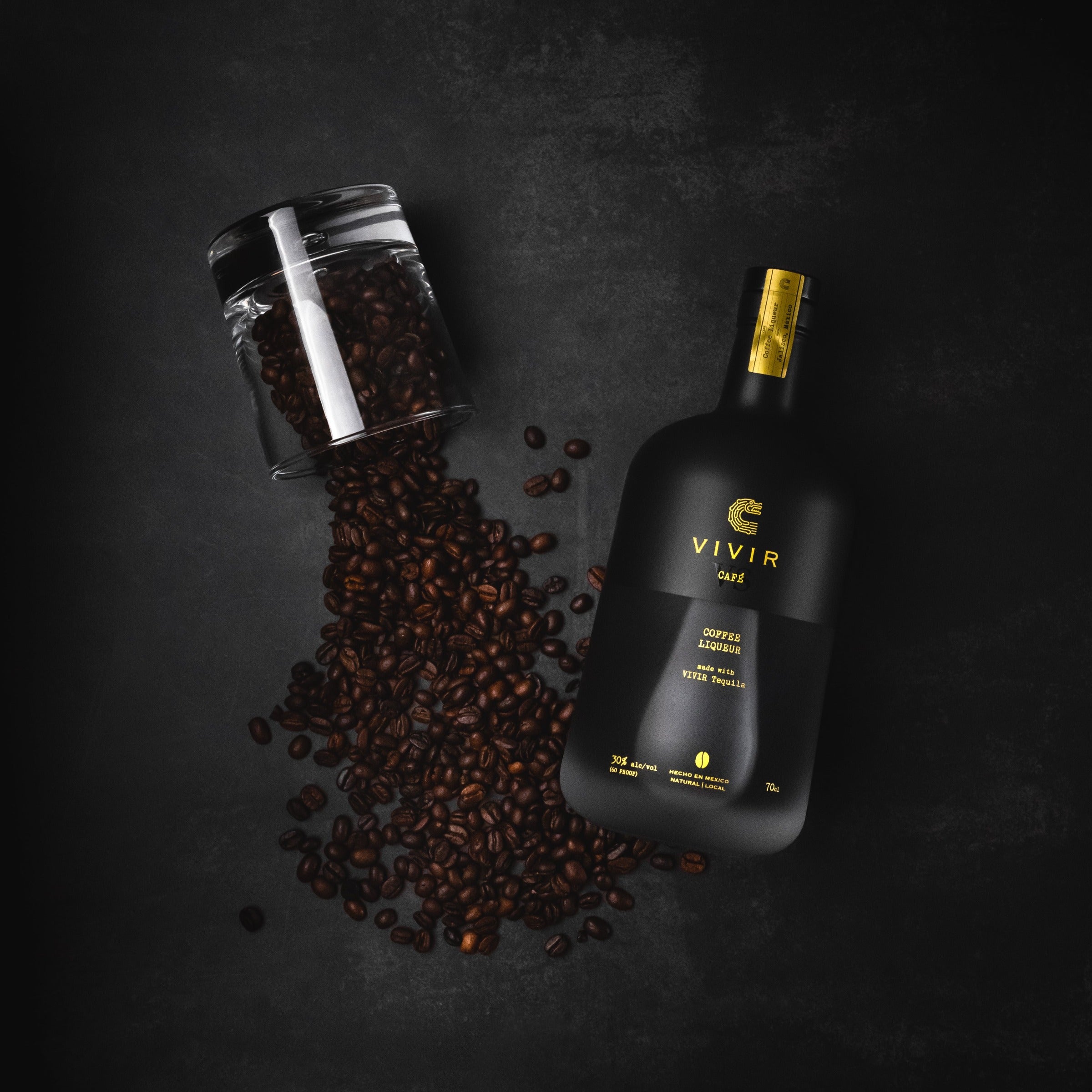 A bottle of VIVIR Café VS is positioned next to a glass of spilt coffee beans.